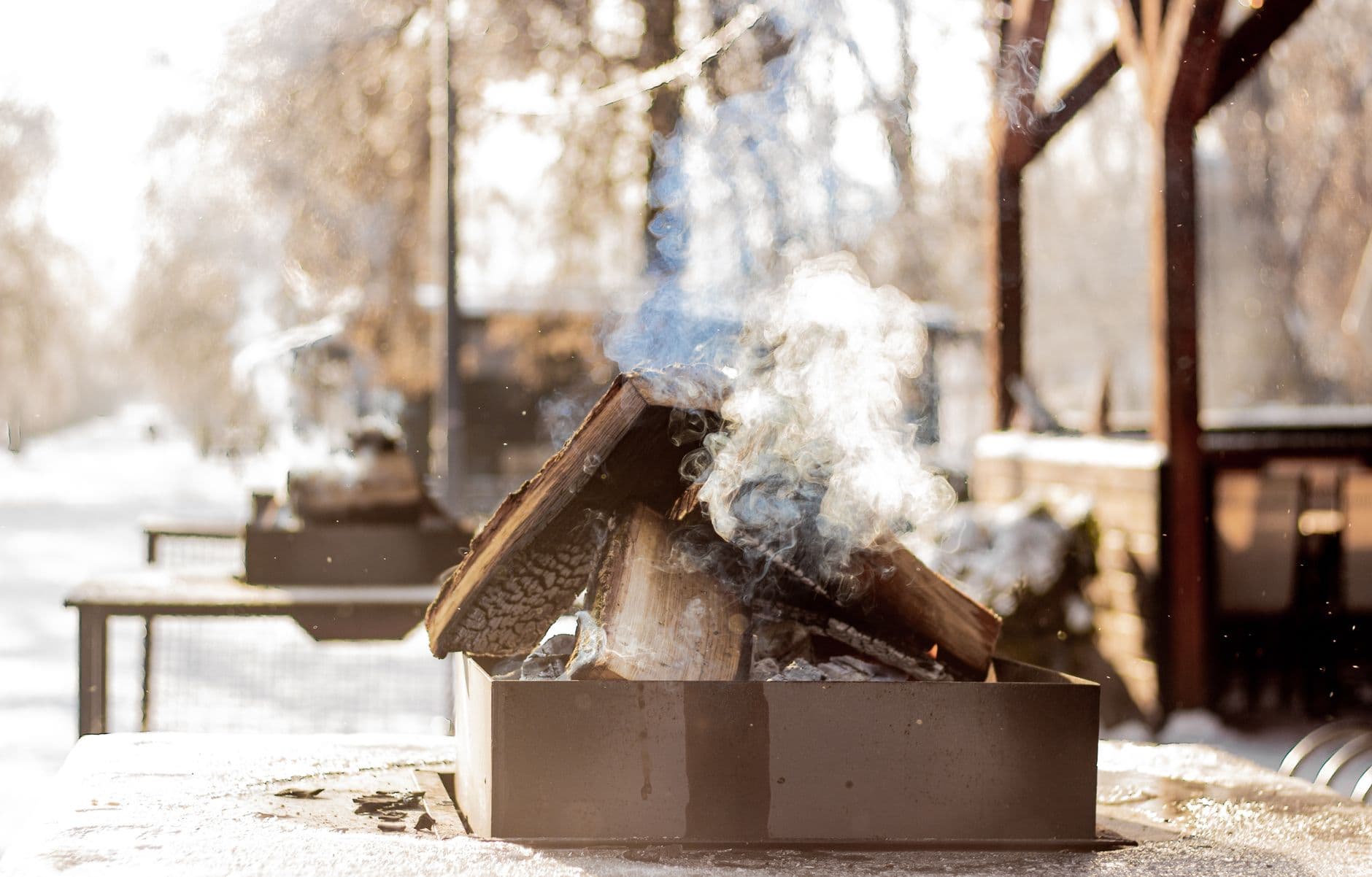 Smoky outdoor fireplace burning in a wintry setting, perfect for cozy outdoor gatherings.