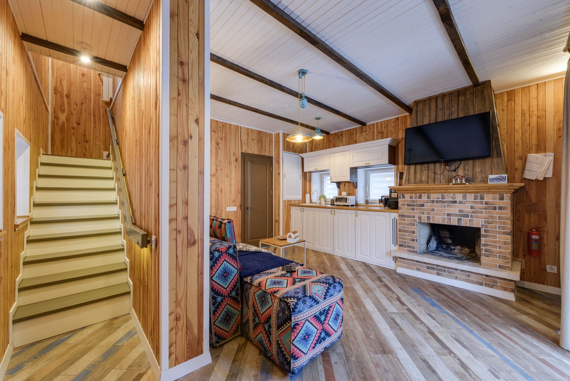 Warm wood-paneled room featuring a fireplace, TV, and kitchen area.